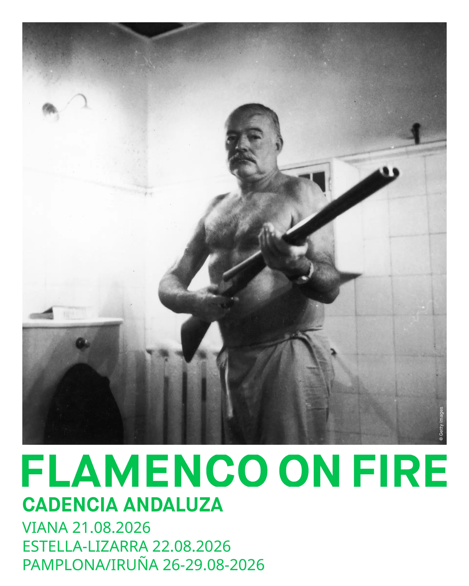 Black-and-white photo of a shirtless older man with a mustache holding a long pole or tube indoors, in a tiled room.