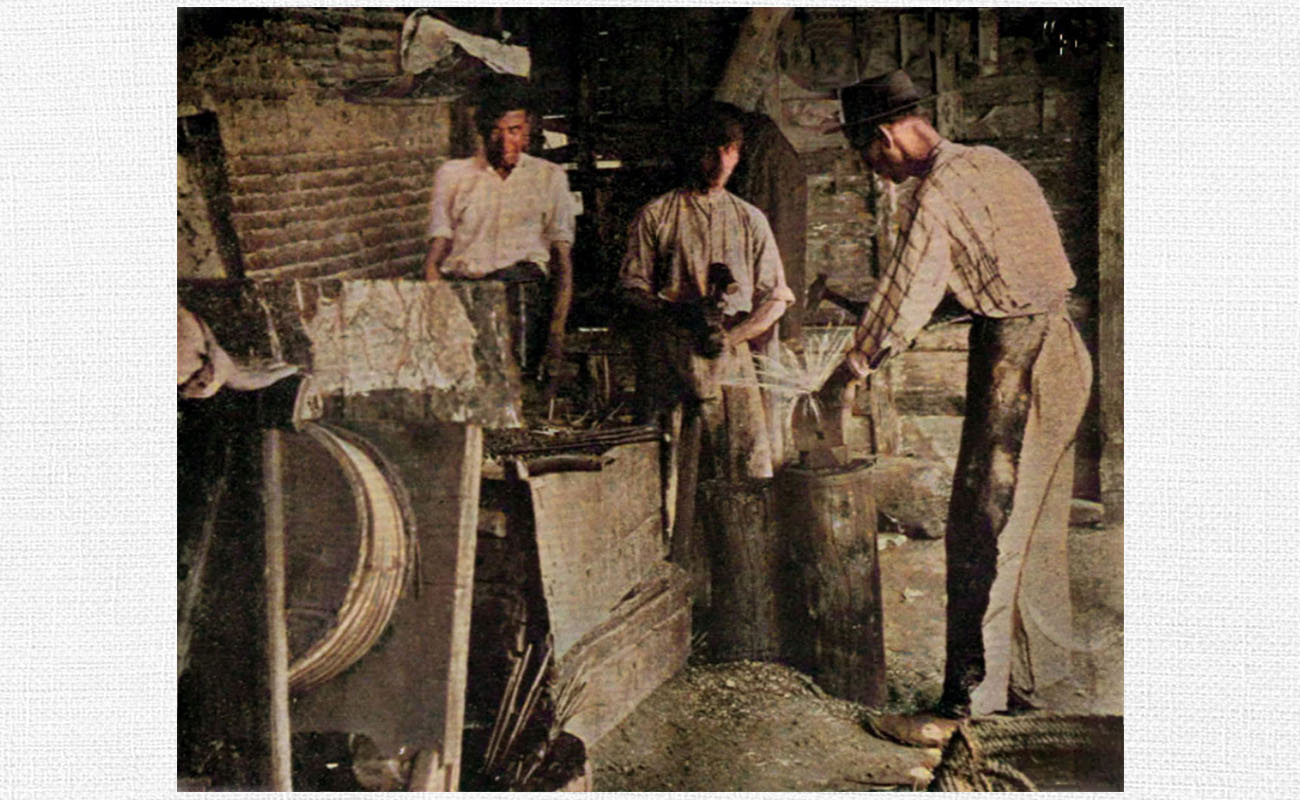 Manuel Cagancho –al fondo, con camisa blanca– e hijos. Reportaje sobre las fraguas de Triana, 1912.