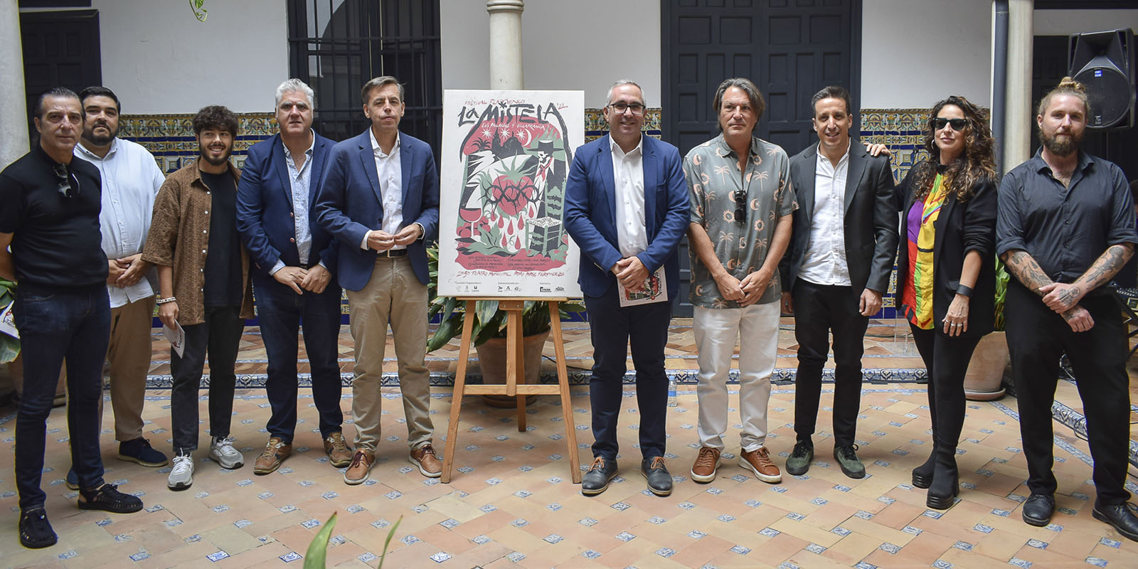 Artistas posando al lado del cartel