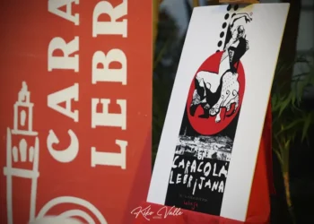 Gallery display: a white-framed poster on a wooden easel featuring a black-and-white illustration inside a red circle, beside a bold red banner with white letters.