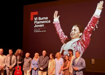 Group of people on a stage posing for a photo, with a large red backdrop featuring a flamenco dancer image and the text VI Suma Flamenca Joven and Comunidad de Madrid behind them.